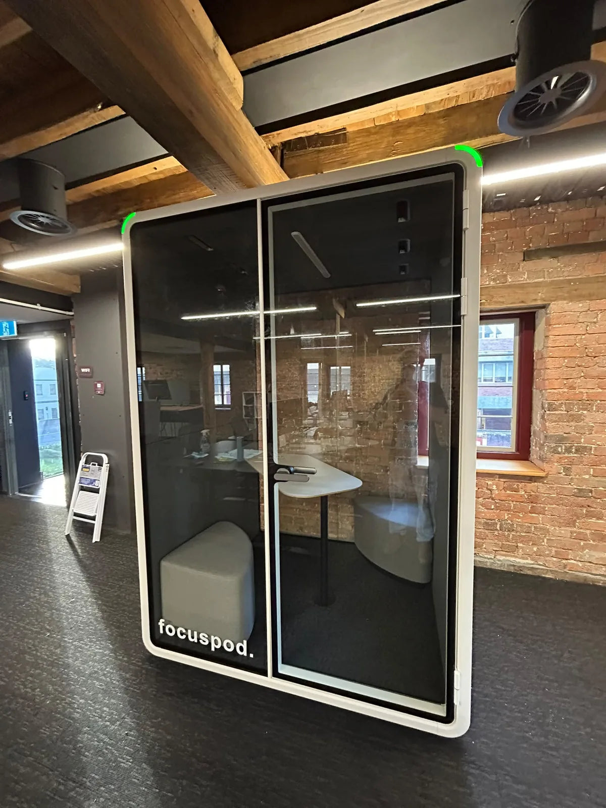 FocusPod Duo with white exterior and glass front beside exposed brickwork in a Launceston coworking space.